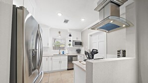 A modern kitchen with white cabinetry, stainless steel appliances, and a central island. - The Queen's Gambit I (Houston)