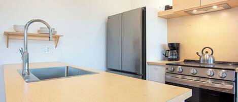 A modern kitchen with a wooden countertop, stainless steel appliances, and a built-in oven.