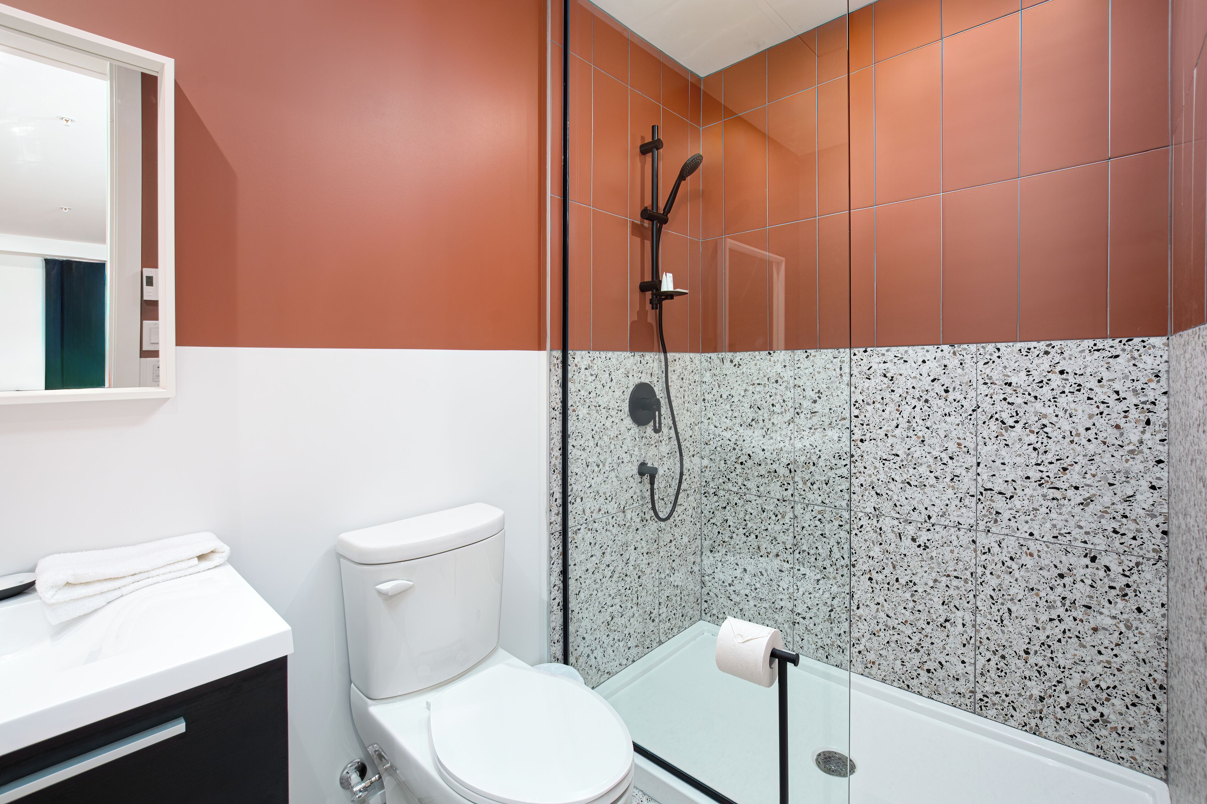 Un baño moderno con un inodoro blanco, cabina de ducha de vidrio y un lavamanos blanco.