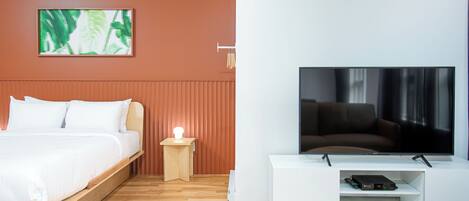 Una habitación de hotel moderna con una cama, un televisor, una mesita y una obra de arte colgada en la pared.