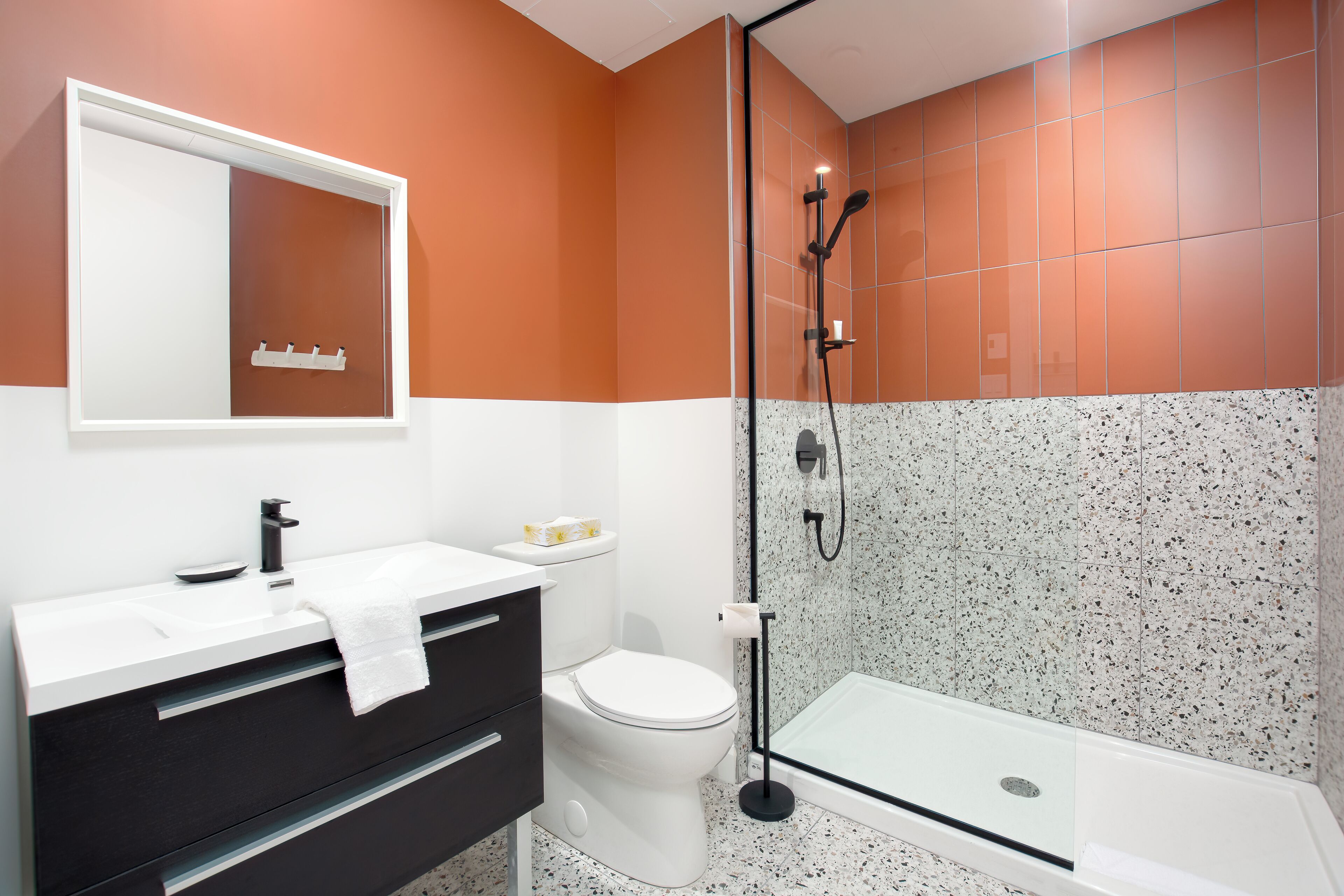Ein modernes Badezimmer mit weißem Waschbecken, schwarzem Waschtisch, weißer Toilette und einer Duschkabine.