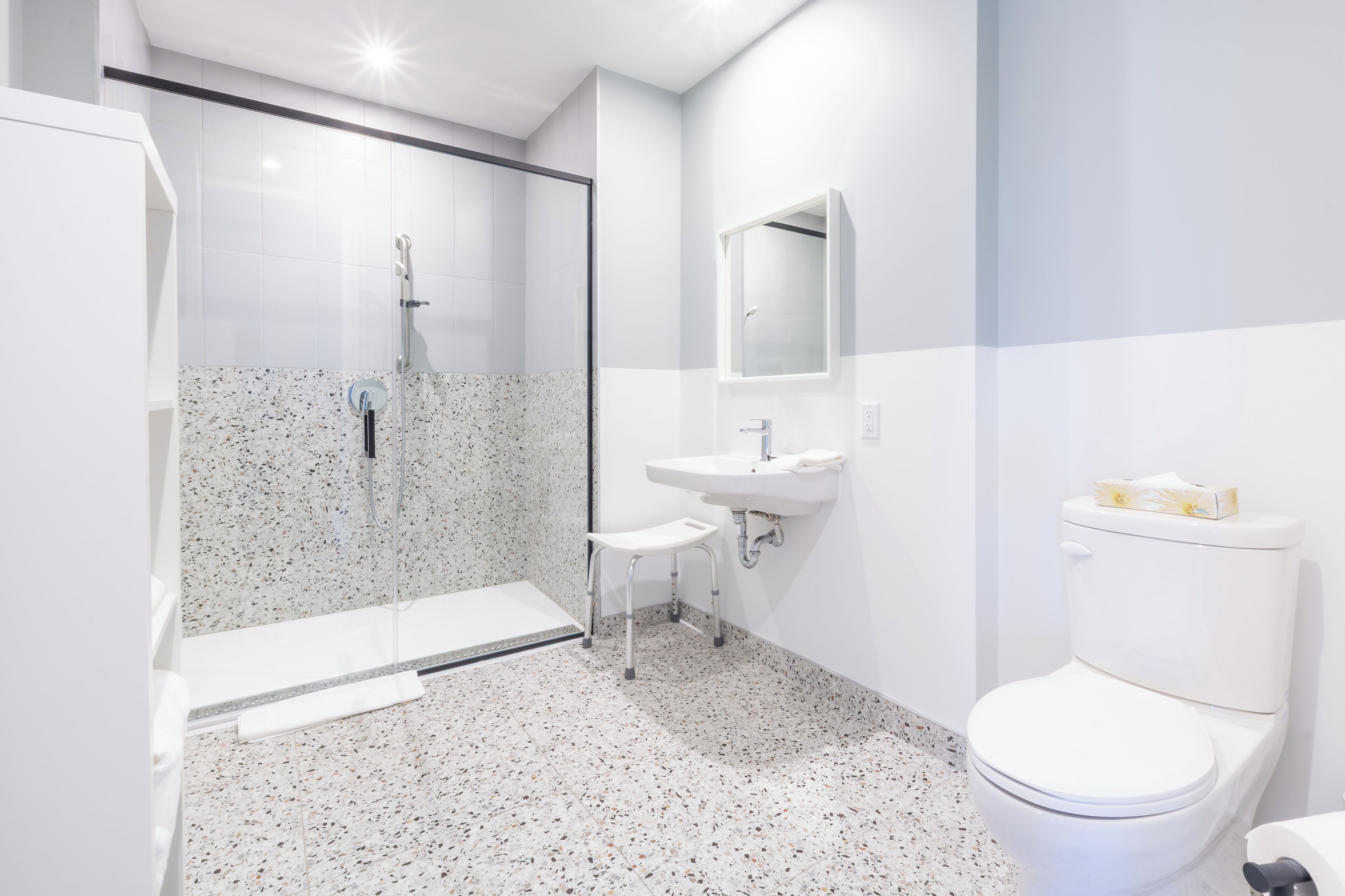 A modern bathroom with a glass-enclosed shower, a white sink, and a toilet.