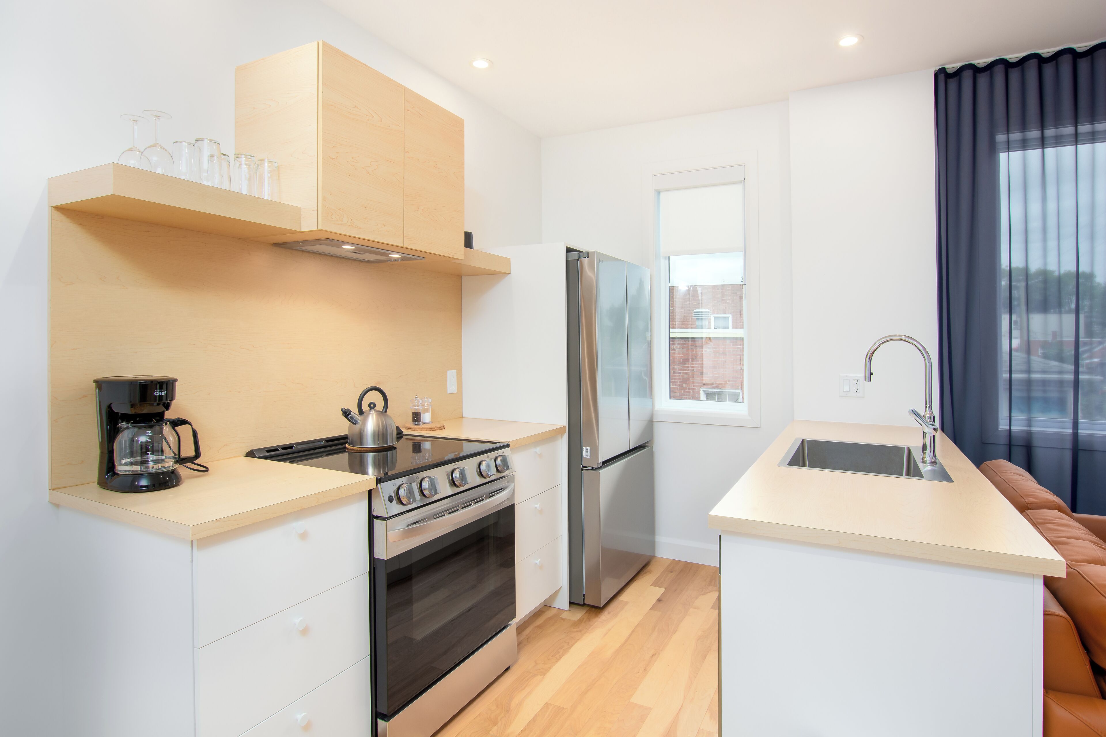 A compact kitchen with a stove, oven, refrigerator, and a small sink.