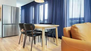 Une cuisine moderne avec un réfrigérateur en acier inoxydable, une table à manger avec quatre chaises et un canapé jaune.