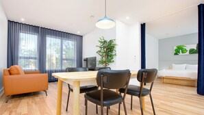 Un salon moderne comprenant un coin repas, un canapé, un téléviseur et une plante.