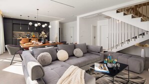 A modern living room with a grey sectional sofa, a coffee table, and a staircase with a minimalist design. - Luxury Villa Lux with Heated Pool (Kaštel Kambelovac)