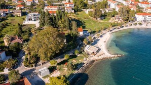 An aerial view of a coastal residential area with houses, a beach, and clear blue waters. - Luxury Villa Lux with Heated Pool (Kaštel Kambelovac)