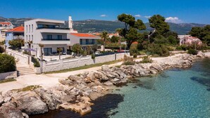Un bâtiment moderne à deux étages, doté d’un mur de soutènement en pierre et offrant une vue dégagée sur la mer.