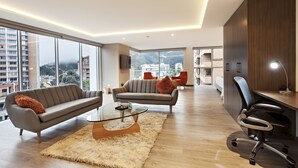 A modern living room with a sofa, armchair, and glass coffee table. - San Juan Hotel Boutique Pasto (San Juan de Pasto)