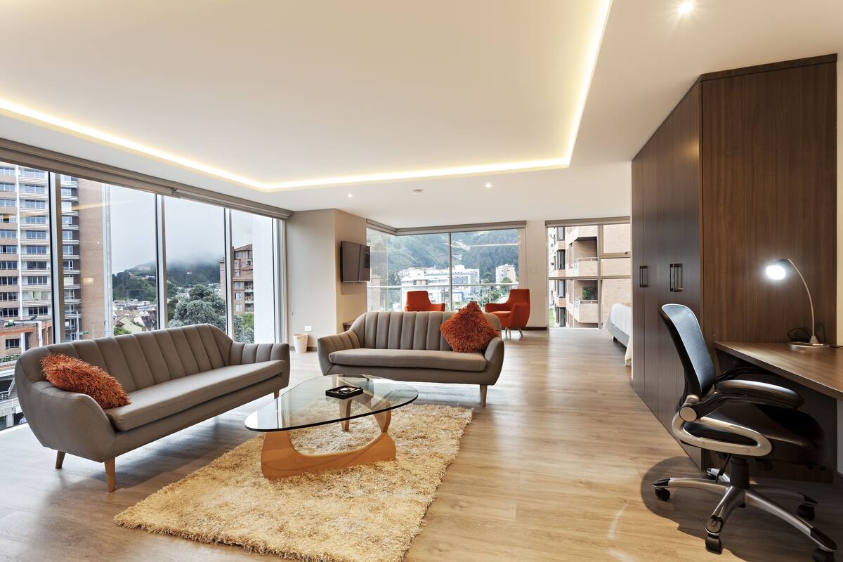 Ein modernes Wohnzimmer mit Sofa, Sessel und Glastisch.