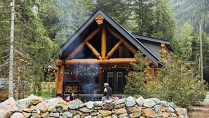 A log cabin with a stone wall in front, surrounded by trees. - Escape to a cabin in the woods (Sunshine Valley, BC, Canada) (Sunshine Valley)