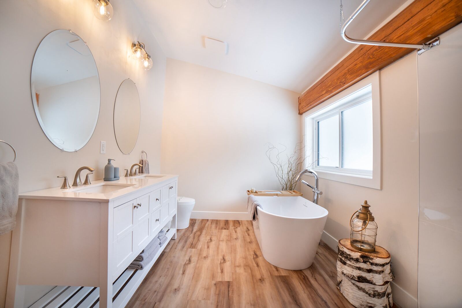 A modern bathroom with a freestanding bathtub, a vanity with a mirror, and a window providing natural light.
