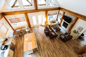 Een ruime woonruimte met een open haard, houten vloeren en een hoog plafond met dakramen.