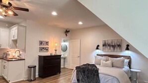 A bedroom with a bed, bedside tables, a nightstand, a dresser, a ceiling fan, and a door. - Studio Apartment with Office Space at Lake Guntersville - Scottsboro, AL (Scottsboro)