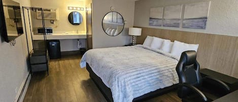 Habitación de hotel con cama, escritorio, silla y espejo.
