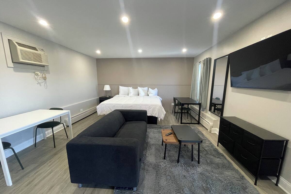 Une chambre d’hôtel moderne équipée d’un lit, d’un bureau, d’un canapé, d’une table à manger et d’un téléviseur.