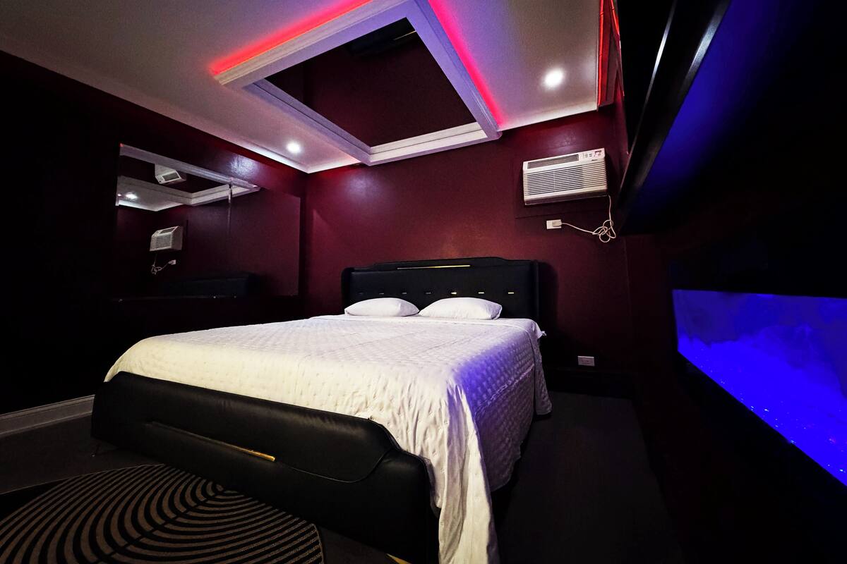 Une chambre moderne équipée d’un lit, de la climatisation intégrée et d’un luminaire au plafond.