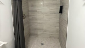 A shower area with a glass door, a showerhead, and a toilet. - Stone Creek Inn (Worth)