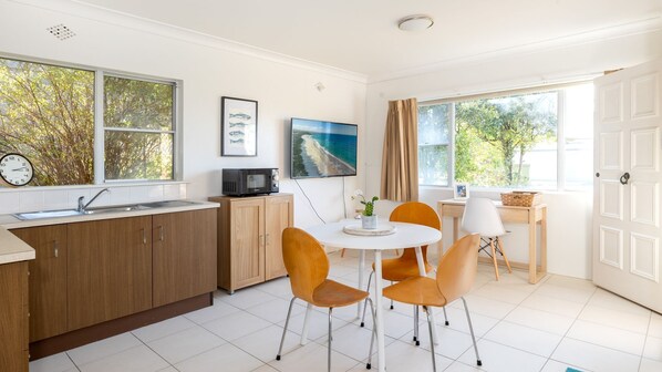 Una cocina moderna con comedor, armarios de madera, un fregadero y un amplio ventanal con vistas a árboles.