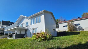 A two-story house with a balcony, a garage, and a small garden with plants. - Hôtel à la maison - Chalet Lola (St-Tite)