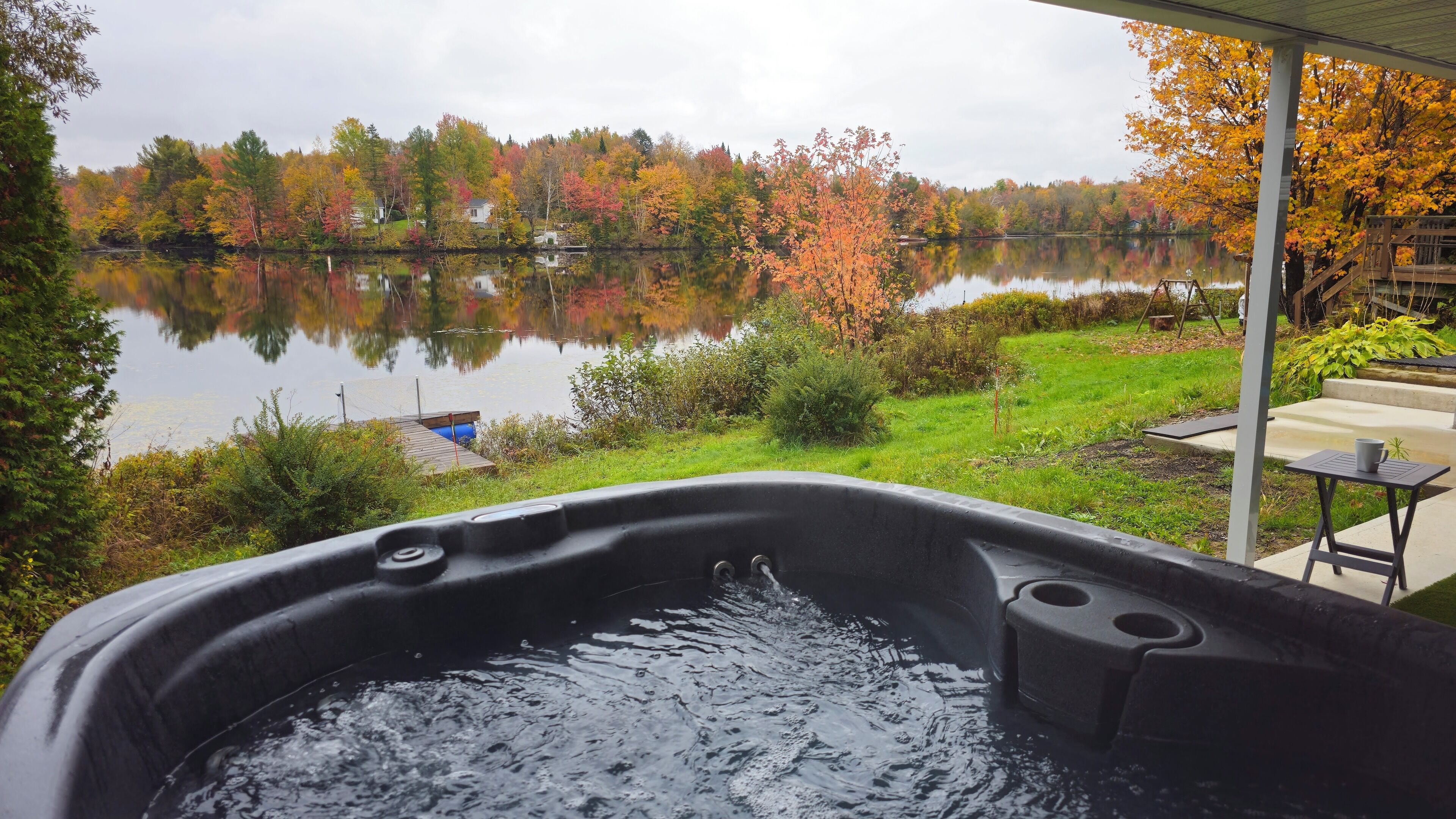 A hot tub with a view of a lake and autumn foliage.