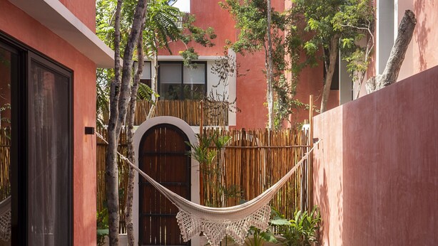 A pool area with a wooden deck, a hammock, and a bamboo fence. - Casa Ananta (Tulum)