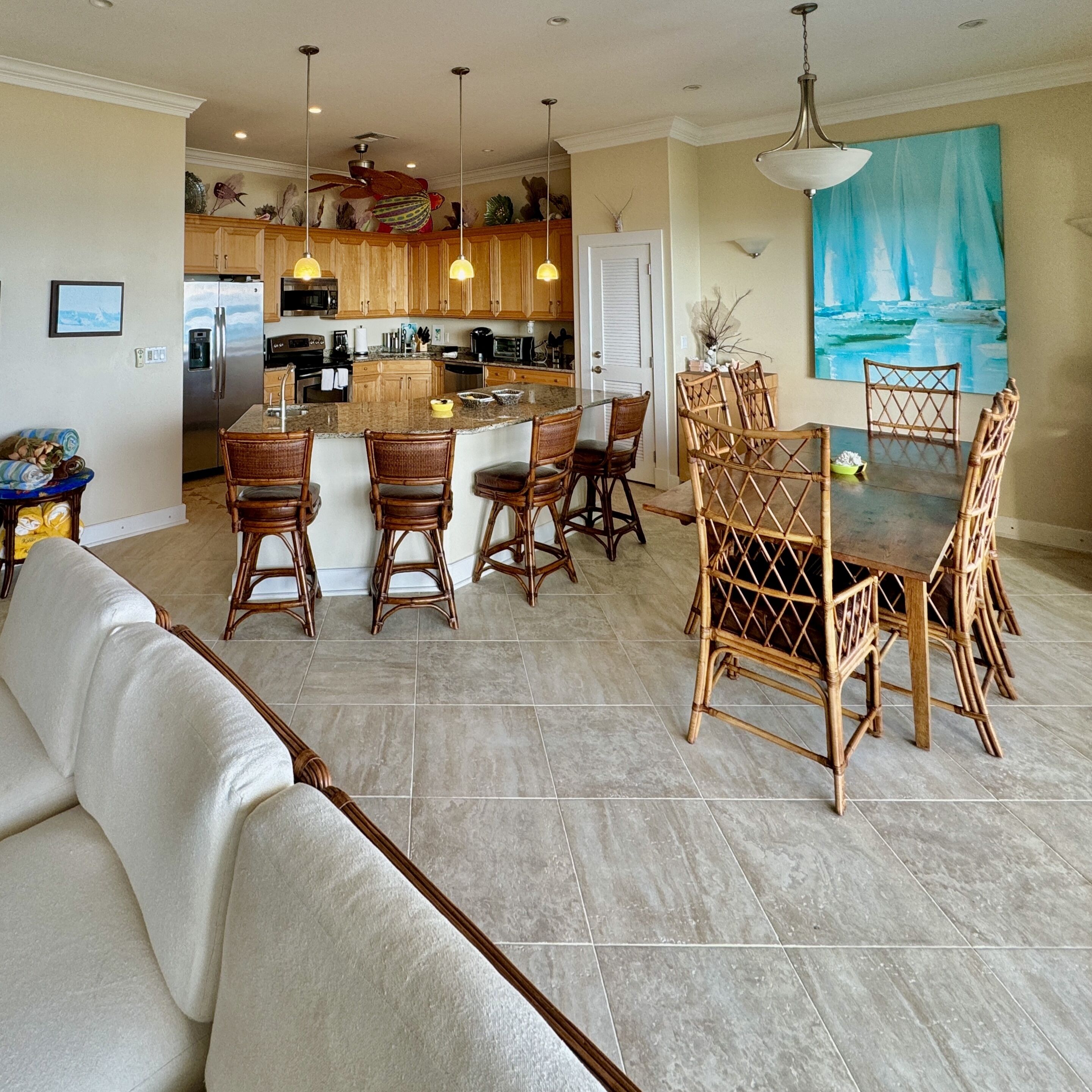 Amplia sala de estar con un sofá grande, una mesa de comedor con sillas y una cocina al fondo.