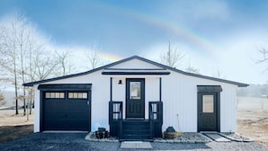 A single-story building with a black garage door, a front door, and a small porch with steps.
