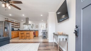 Una cucina moderna con mobili in legno, un angolo bar e una ventola a soffitto.