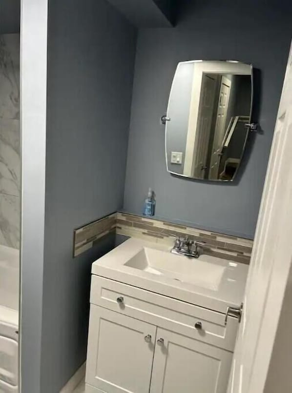 Un baño con tocador blanco, espejo y lavamanos.