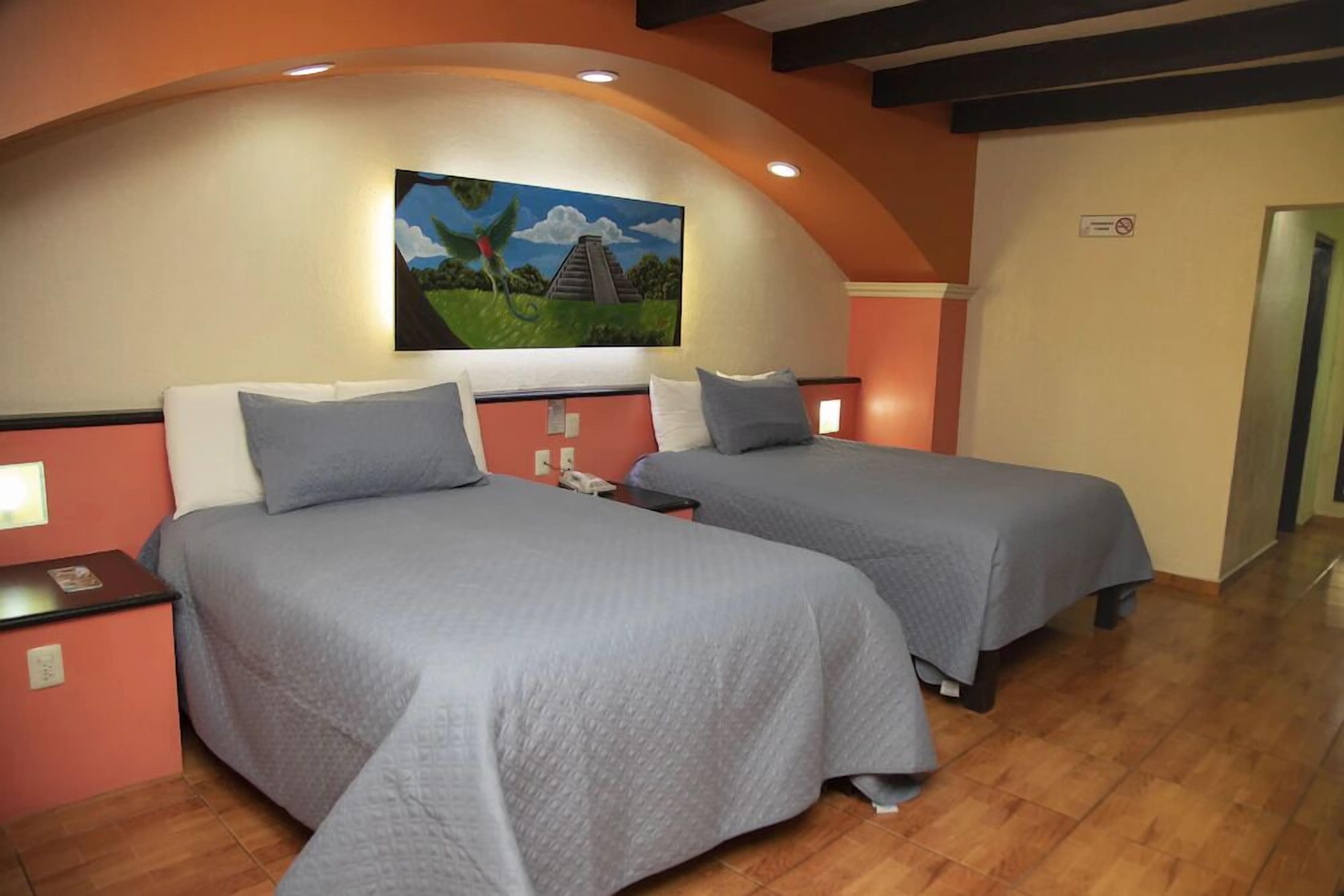 Una habitación de hotel con dos camas, un cuadro de un paisaje en la pared y suelo de madera.