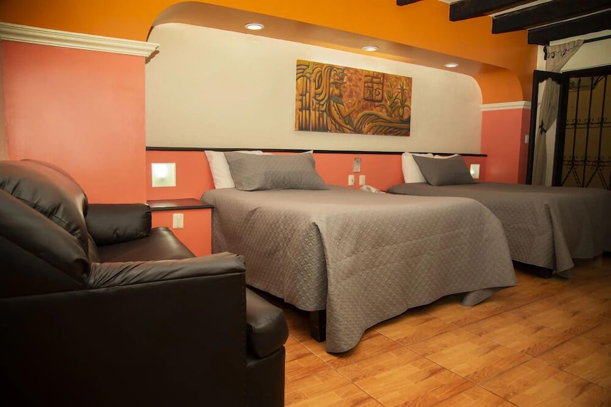 A hotel room with two beds, a sofa, and a large painting on the wall.