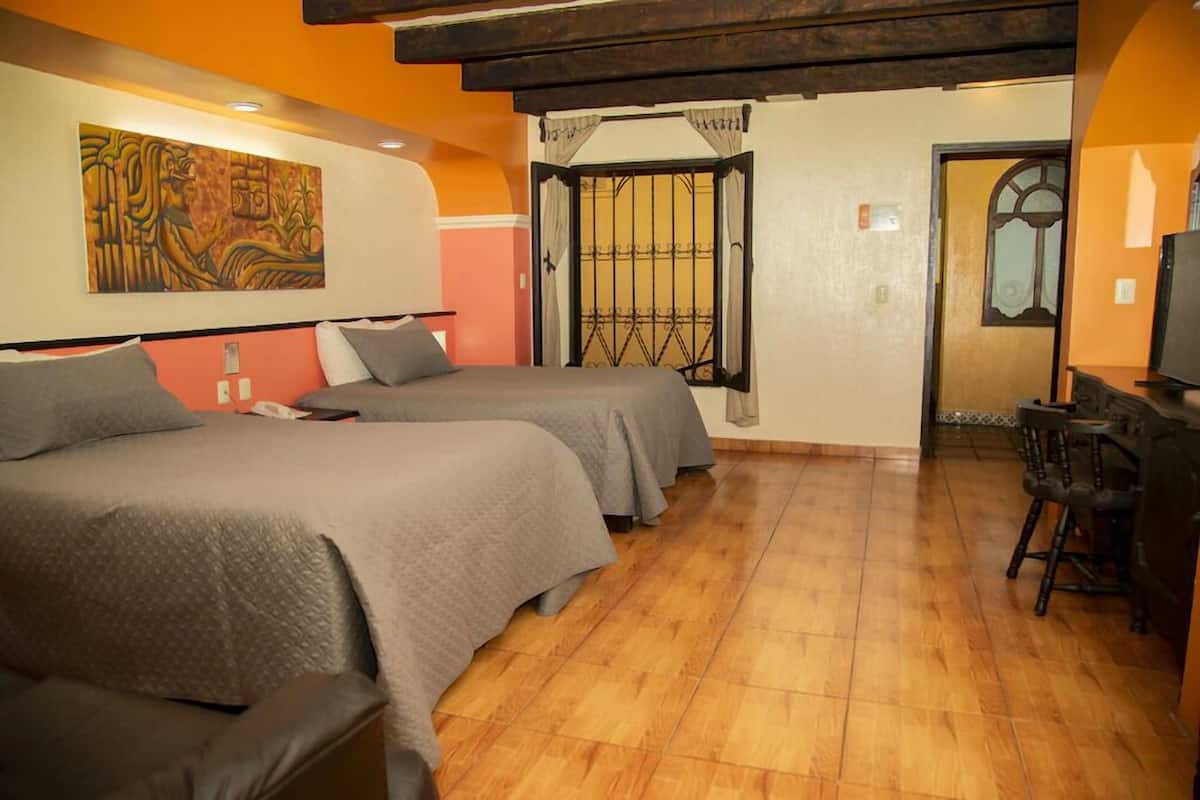 A hotel room with two beds, a wooden floor, a painting on the wall, and a TV on a wooden cabinet.