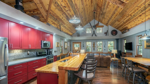 Una cocina amplia con armarios rojos, una isla de madera y un comedor espacioso con taburetes de bar.