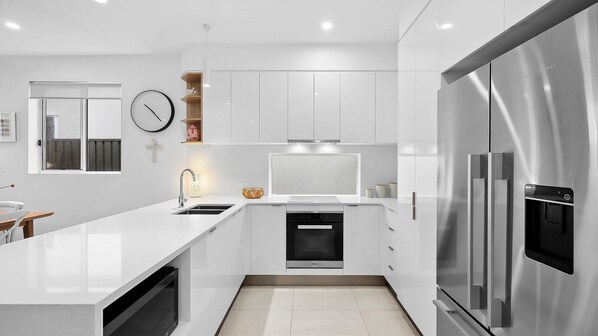 A modern kitchen with white cabinetry, stainless steel appliances, and a large island.