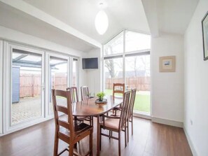 Enjoy meals in this dining area with a table and chairs, overlooking a backyard view through large windows.