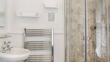 A bathroom with a glass-enclosed shower, a white sink, and a towel rack.