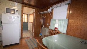 A compact kitchen with a refrigerator, microwave, and a dining area with a table and chairs. - Lakeside Getaway, Just Steps Away from Fourth Lake Here at Stiefvater's Lakeside Cottages! (Inlet)