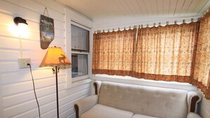 A room with a patterned sofa, a lamp, and a window with curtains. - Lakeside Getaway, Just Steps Away from Fourth Lake Here at Stiefvater's Lakeside Cottages! (Inlet)