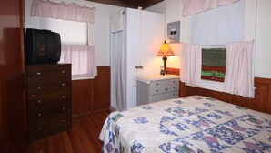 Een slaapkamer met een bed, een kaptafel, een dressoir, een lamp en een televisie.