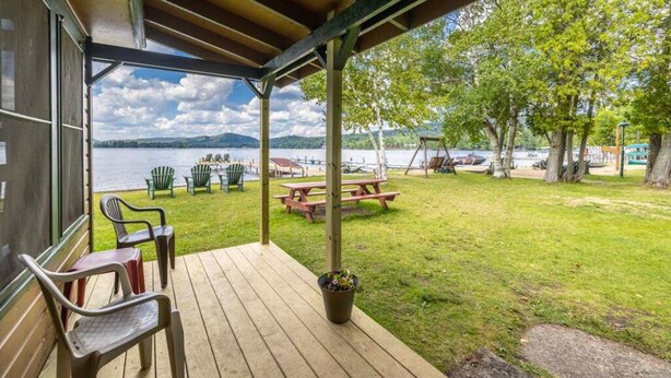 Et overdækket udendørs område med træterrasse, picnicborde og stole.