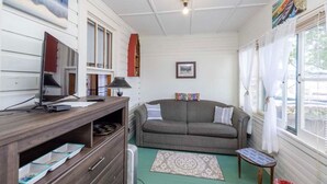 En hyggelig stue med et fjernsyn, en tv-reol i træ, en sofa og et lille bord.
