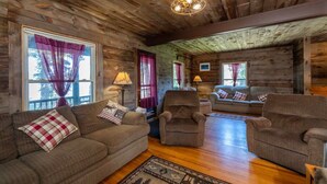 A cozy log cabin interior with a wooden ceiling, a fireplace, and a living area with sofas and armchairs. - Lakeside House View Overlooking Beautiful 4th Lake Here at Stiefvater's Lakeside Cottages (Inlet)