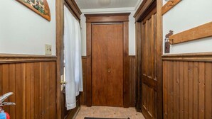 A hallway with wooden paneling, a door with a brass handle, and a black doormat. - Lakeside House View Overlooking Beautiful 4th Lake Here at Stiefvater's Lakeside Cottages (Inlet)