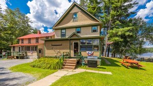 A two-story house with a front porch, a small front yard, and a picnic table. - Lakeside House View Overlooking Beautiful 4th Lake Here at Stiefvater's Lakeside Cottages (Inlet)