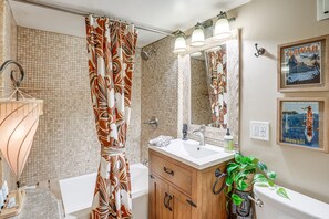 Une salle de bain équipée d’une douche, d ’un lavabo, de toilettes, d’un miroir et d’un porte-serviettes.