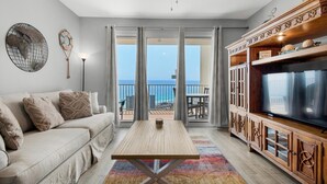 En stue med sofa, sofabord, TV-møbel og balkon med havudsigt.