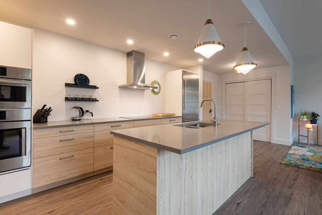 A modern kitchen with a central island, stainless steel appliances, and pendant lighting.