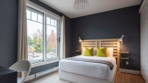 Une chambre à coucher moderne avec une grande fenêtre, un lit avec des oreillers, une chaise et un bureau.