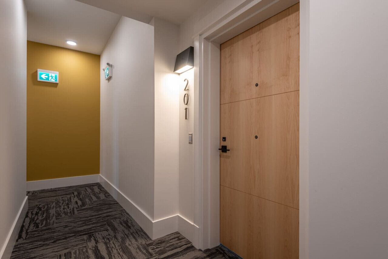 A hallway with a wooden door marked "201", a wall with a number "201" sign, and an exit sign.